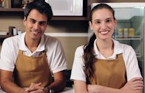 A smiling young man and woman wearing aprons