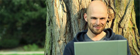 A smiling man sitting in front of a tree learning about the environment